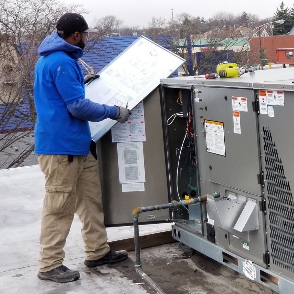 Technician inspecting a commercial rooftop HVAC unit